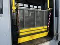 A wheelchair lift with a metal grate and yellow stripes positioned at the back of a 2018 Chevrolet Express vehicle