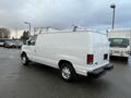 White 2013 Ford Econoline cargo van with a roof rack facing to the right