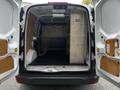 The interior of a 2014 Ford Transit Connect with open double rear doors showing a spacious cargo area and a metal storage unit on one side