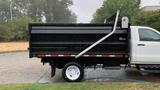 A white 2021 International CV515 dump truck with a black dump bed is parked on a street with rain falling