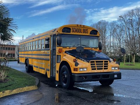 A 2005 Blue Bird school bus designed to carry 48 passengers painted in bright yellow with black stripes and multiple side mirrors