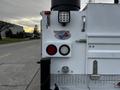 A rear view of a 2016 Ford F-550 showing red and white tail lights and a round reflective light with a badge indicating a weight limit of 55 tons