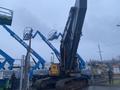 A 2014 John Deere 350G excavator with a large tracked base and a raised arm is positioned prominently in the foreground