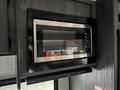 A stainless steel microwave oven installed in a kitchen area with a black frame and control panel