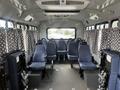 Interior of a 2012 Chevrolet Express showing empty rows of grey upholstered seats and large windows with patterned curtains