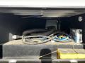 A storage compartment filled with coiled hoses various electrical cords and a portable power outlet