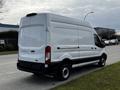 A white 2020 Ford Transit van with a tall roof and sliding side door parked on the street