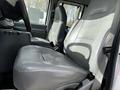 Two grey front seats of a 2004 Ford Econoline with a console in between and seat belts attached