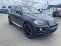 A 2009 BMW X5 SUV in dark color with black alloy wheels and side steps showcasing its sporty design and luxury features
