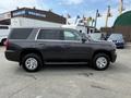 A 2016 Chevrolet Tahoe in dark gray with chrome wheels parked on a lot showcasing its side profile