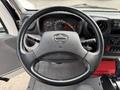 A black steering wheel with a silver Hino emblem at the center and various dashboard gauges visible in the background
