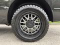 A close-up of a 2018 RAM 1500 wheel showcasing a black multi-spoke rim and an off-road tire with aggressive tread pattern