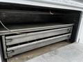 A 2016 Ford F-550 featuring a storage compartment with two metallic sliding drawers and a flat work surface