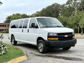 A white 2021 Chevrolet Express van with a black grille and chrome wheels parked on a street