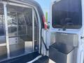 2007 Chevrolet Express van interior showing a metal cage divider with an empty cargo area on one side and an open side door with a storage compartment on the other side