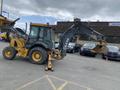 A yellow and black 2012 John Deere 310SJ backhoe loader with a front bucket and rear excavator attachment
