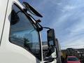 A close-up of the driver's side mirror and window of a 2024 Isuzu FVR truck showcasing the vehicle’s sleek design and visibility features