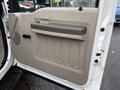 The interior door panel of a 2008 Ford F-550 featuring a gray armrest a door handle and textured surfaces