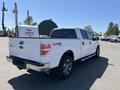 A white 2014 Ford F-150 pickup truck with chrome accents and a different style rear tailgate visible in the foreground
