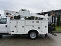 A 2008 Ford F-550 with an Altec bucket truck attached featuring compartments for tools and equipment and a hydraulic lift arm extended upward