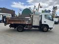 A 2008 Mitsubishi Fuso FE180 dump truck with a rusty cargo bed and a silver side compartment is parked at an industrial location