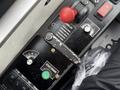A control panel with various buttons and levers including a red emergency stop button a start engine button and indicators for vehicle operations