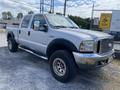 A silver 2007 Ford F-350 SD with a spacious crew cab and chrome accents parked on gravel