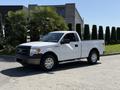 A 2014 Ford F-150 in white with a black grille and silver wheels parked on a driveway