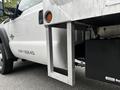 A 2011 Ford F-550 with a metallic flatbed and a black storage box attached to the side of the truck