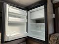 Interior of a 2018 Westland Travelaire refrigerator with open doors displaying empty shelves and an ice tray compartment