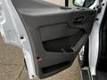 The interior door panel of a 2023 Ford Transit featuring a smooth gray surface with a handle and storage compartment