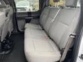 A gray cloth interior of a 2016 Ford F-150 truck showcasing the rear bench seat with seat belts and textured upholstery