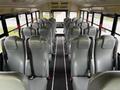 Interior of a 2013 International 4200 school bus featuring rows of gray seating with seat belts and a central aisle