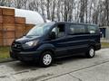 A blue 2020 Ford Transit van is parked with sliding doors open displaying spacious seating and a modern design