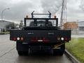 A 2015 Ford F-550 with a flatbed design featuring orange lights and a black mesh guard on the back