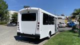 A white 2011 Chevrolet Express bus parked with its rear visible showcasing its large windows and simple design