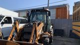 A 2015 Case 580 backhoe loader with a bucket attachment and front loader arms in the foreground