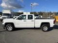 A 2018 GMC Sierra 1500 in white with a crew cab and four-wheel drive parked with its side view visible