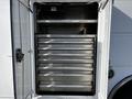 A white door of a vehicle opened to reveal multiple metal storage drawers arranged in a vertical stack