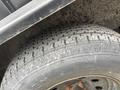 A close-up of a worn tire with a tread pattern mounted on a wheel showing rust on the wheel hub