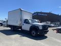 A white 2015 Ford F-450 Super Duty box truck with a silver cargo area and a flat front is parked with its wheels turned