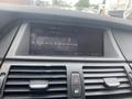 Dashboard of a 2009 BMW X5 showing the radio display and air conditioning controls