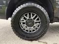 A close-up of a black alloy wheel with a distinctive design mounted on a 2018 RAM 1500 with a rugged all-terrain tire