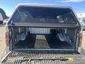 A 2014 Ford F-150 truck bed with a black rubber mat and silver-colored side panels, featuring a roll-up cover on the top