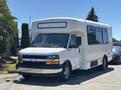 A 2020 Chevrolet Express van with a large windowed passenger area and a white exterior parked in a driveway