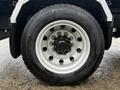 Close-up of a silver aluminum truck wheel with a black Michelins tire showcasing multiple circular holes in the rim
