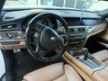 Interior view of a 2011 BMW 7-Series featuring a leather steering wheel a wooden dashboard and advanced control panels