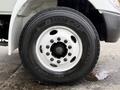 Close-up of a black Dunlop SP 581 tire mounted on a white wheel of a 2006 International 4200 truck with visible lug nuts