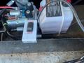 A control switch labeled "HOIST" and "JACK" with a toggle button, located near hydraulic components and a fluid reservoir