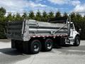 A 2010 Freightliner M2 106 dump truck with a metallic silver bed and dual rear wheels positioned at an angle showing the back and side view